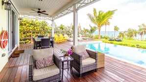 A covered outdoor area with wicker furniture, a pool, and a view of the ocean. - Wild Orchid Hideaway: Lux Beachfront Sanctuary (Governor's Harbour)