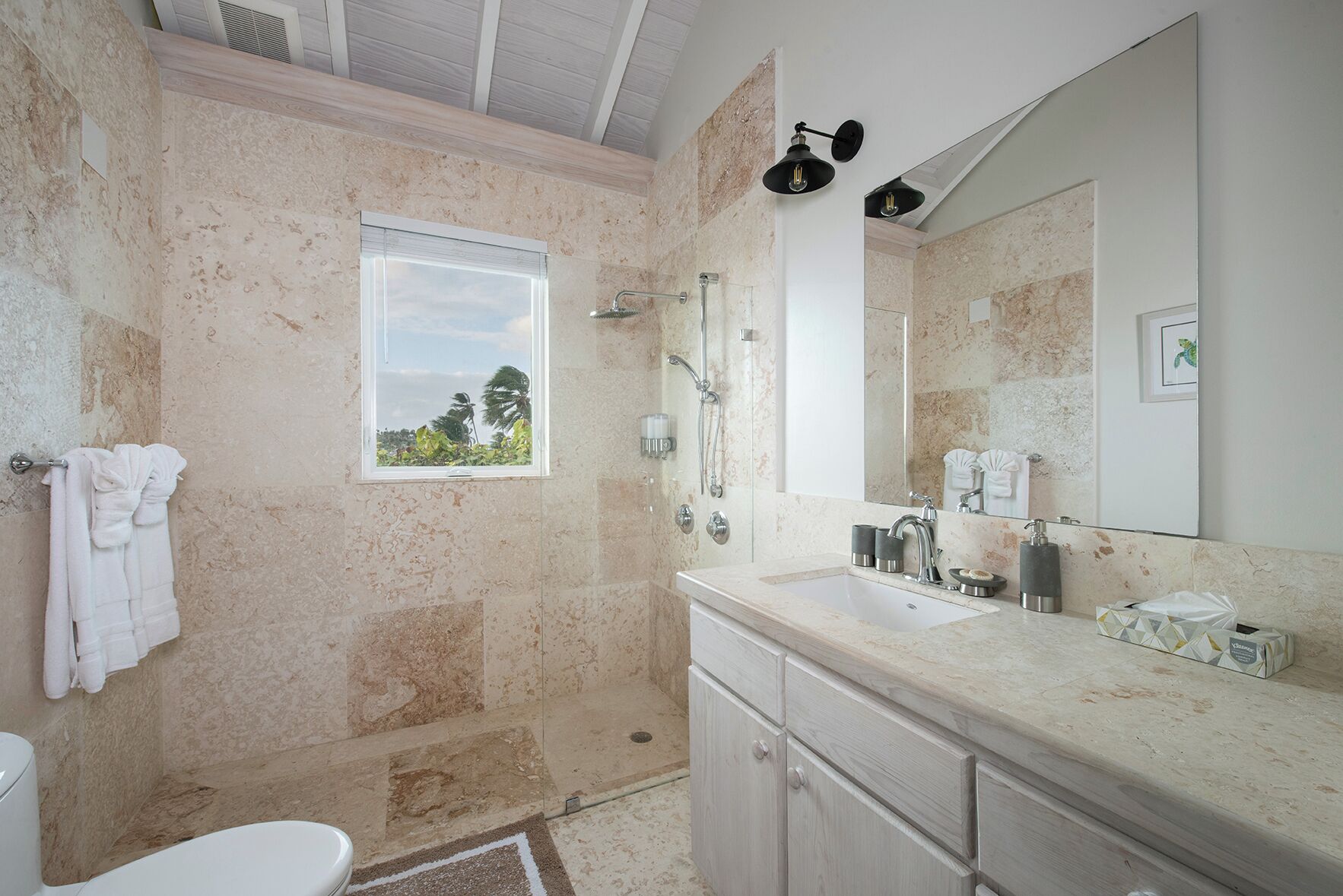 Un bagno con una grande finestra, una doccia, un lavandino con specchio e un water.