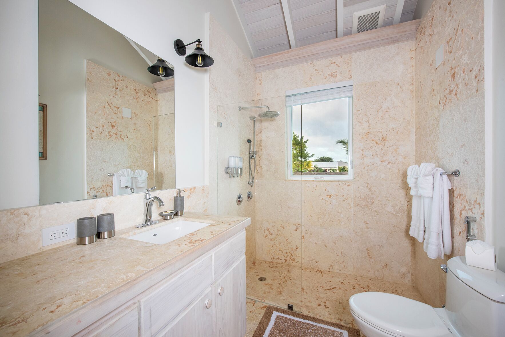 A bathroom with a large mirror, two sinks, a shower, and a toilet.