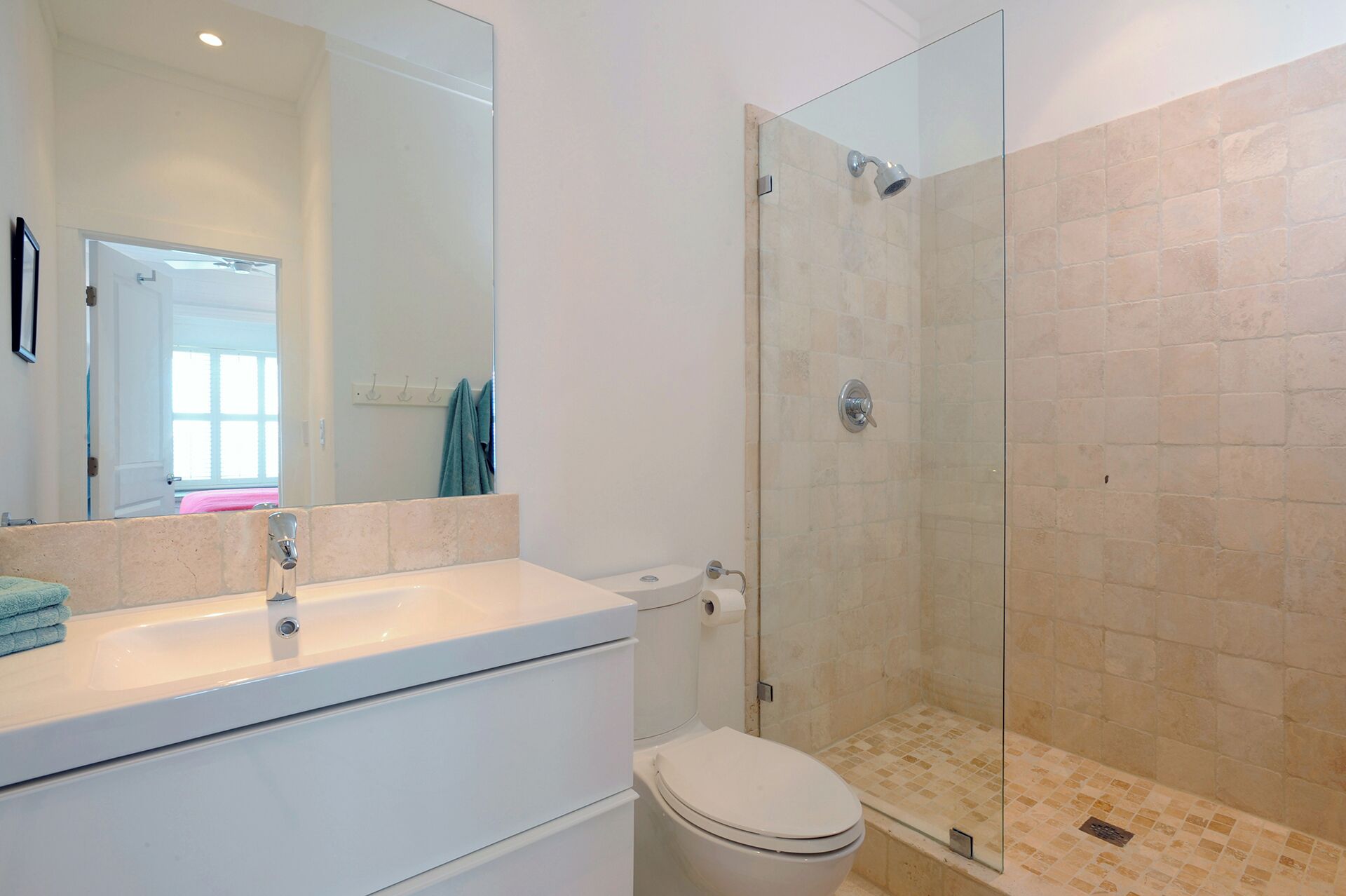 A bathroom with a glass-enclosed shower, a white sink, and a toilet.