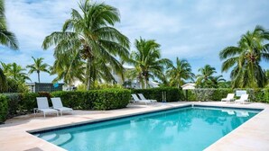 A rectangular pool with white lounge chairs and palm trees in the background. - Oceanfront Bliss: Newly Built Luxury Home With Sunset Views (North Palmetto Point)