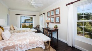 A bedroom with two beds, a desk, and a view of the ocean. - Hilltop Haven: Luxurious Historic Estate With Harbor Views (Governor's Harbour)