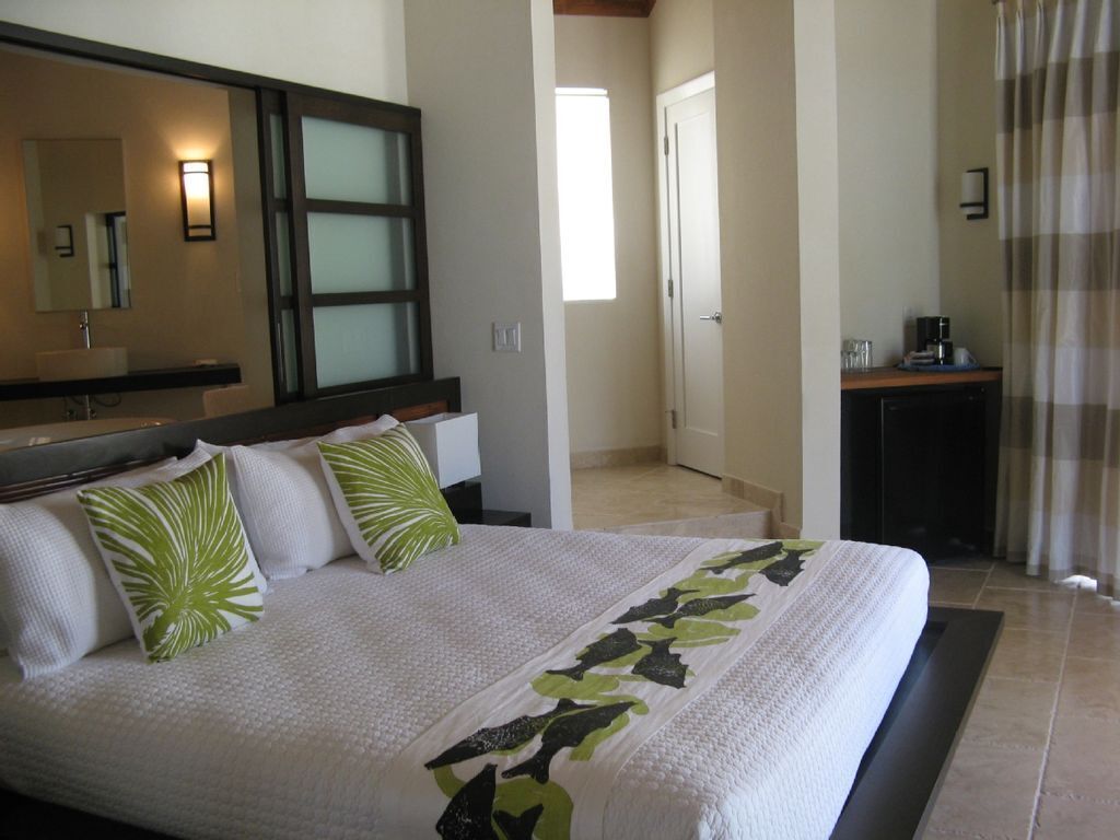 Een hotelkamer met een groot bed, een badkamer met spiegel en een kleine kitchenette.
