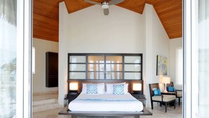 A spacious bedroom with a large bed, a ceiling fan, and a view of the outdoors. - Caribbean Retreat: Private Villa With Panoramic Ocean Views (Governor's Harbour)