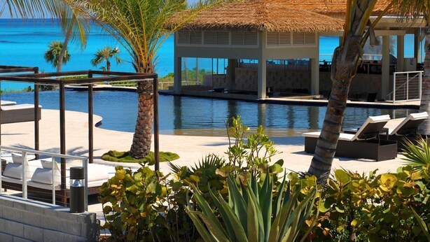 A poolside area with lounge chairs, a thatched-roof structure, and a view of the ocean. - Caribbean Retreat: Private Villa With Panoramic Ocean Views (Governor's Harbour)