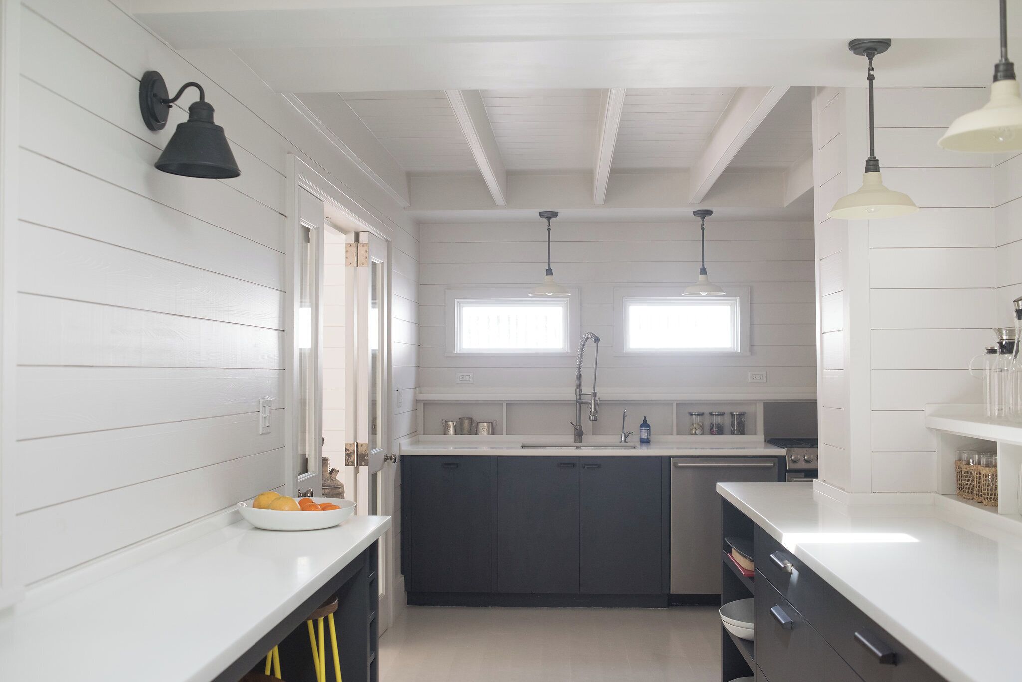 Une cuisine moderne avec des panneaux muraux en bois clair et foncé, un îlot central et des luminaires suspendus.