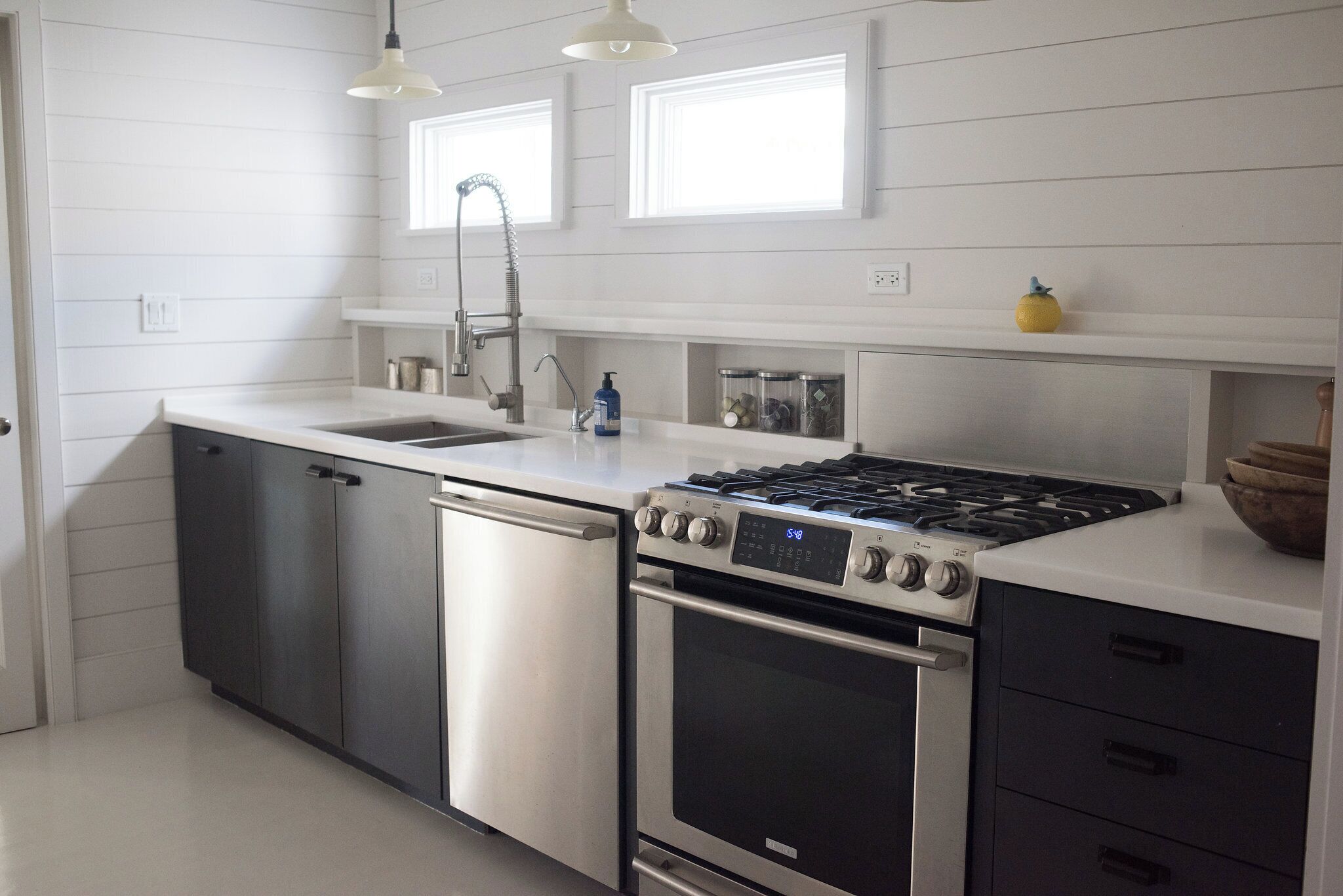 A modern kitchen with stainless steel appliances, a dishwasher, a sink, and a window above the countertop.