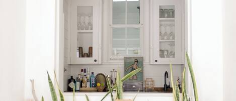 A white kitchen with cabinets, a window, and plants.