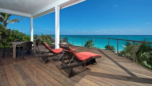A wooden deck with lounge chairs and a table, overlooking a turquoise ocean. - Coastal Luxury: New Beachfront House With Pool (North Palmetto Point)