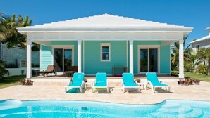 A pool area with a covered patio, lounge chairs, and a clear blue pool. - Coastal Luxury: New Beachfront House With Pool (North Palmetto Point)