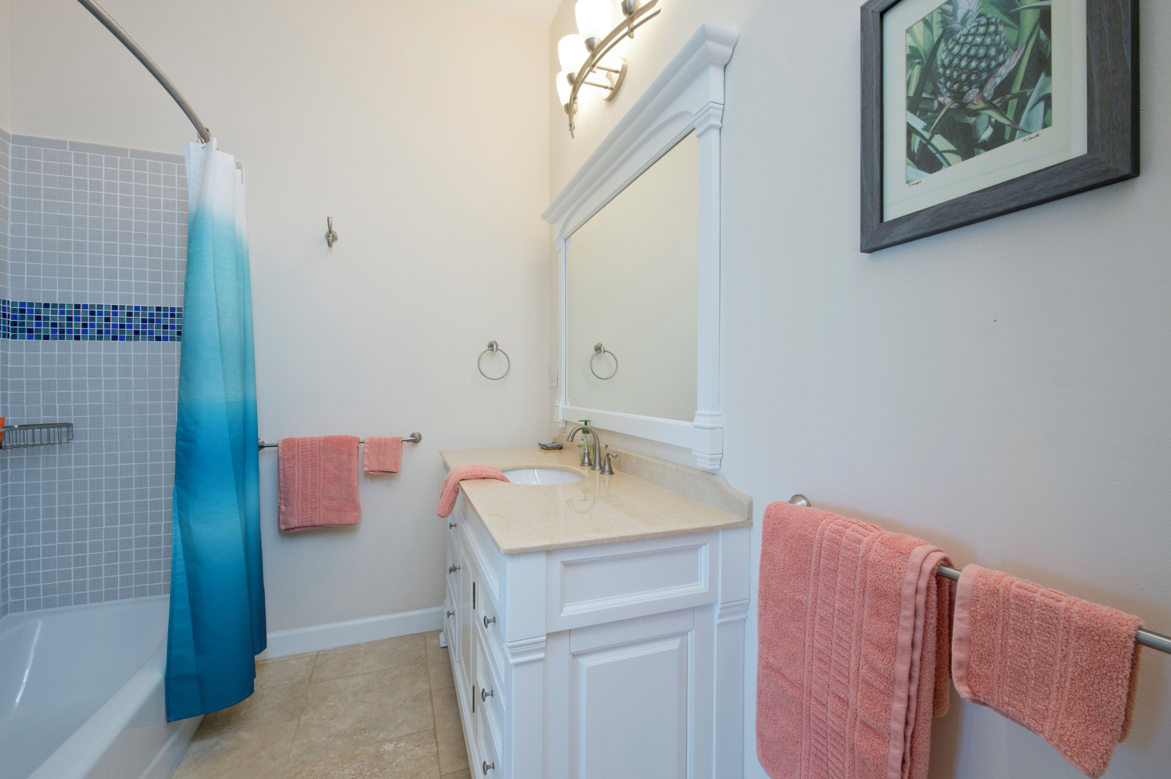 A bathroom with a bathtub, a sink, and a mirror. There are towels hanging on the wall and a shower curtain.