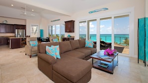 A spacious living area with a large brown sectional sofa, a dining table, and a kitchen area. - Buttonwood Bliss: Lux Condo With Views (James Cistern)