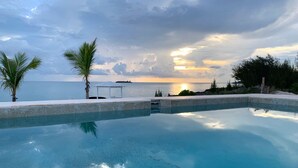 Una piscina con vista sull'oceano e un tramonto.