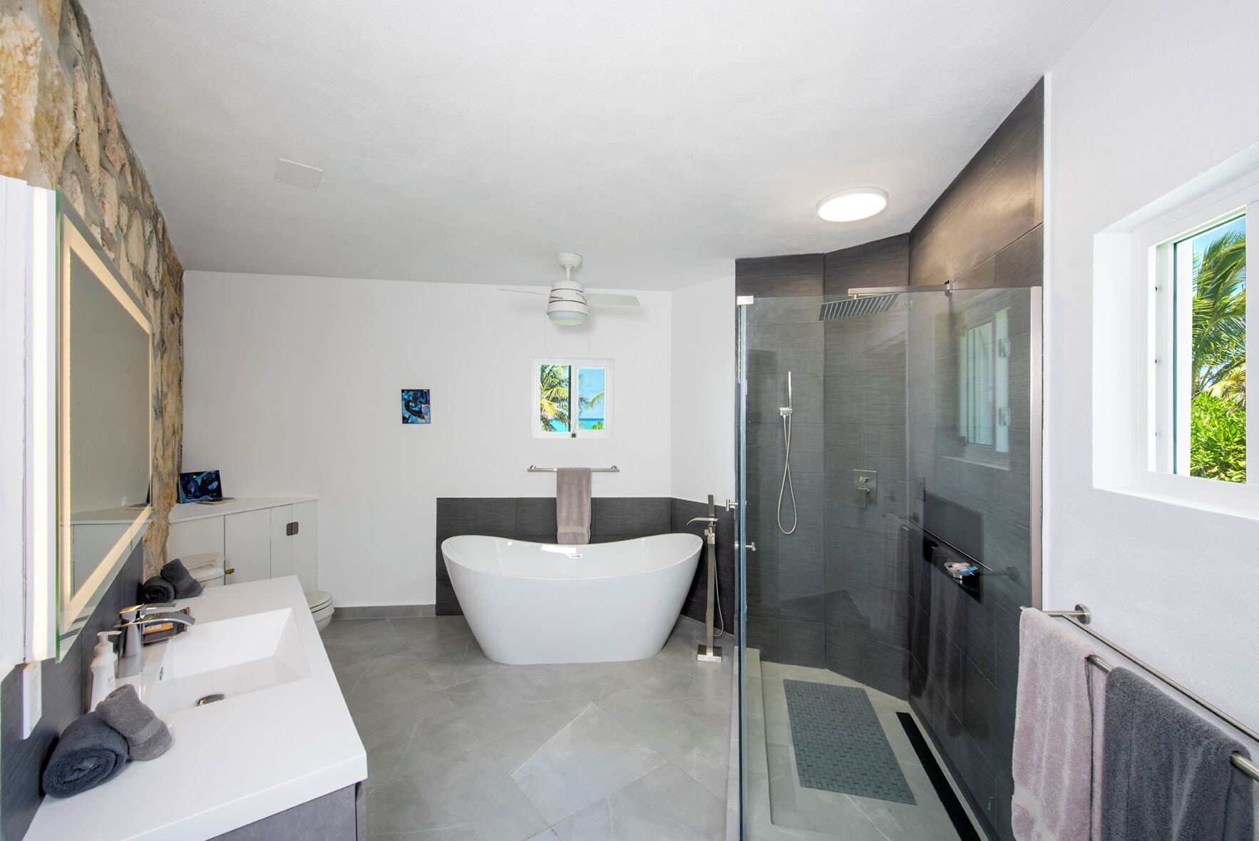 Een moderne badkamer met een vrijstaand bad, een douche met glazen wanden en een grote spiegel.