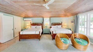 Una habitación con dos camas de madera, un ventilador de techo y una ventana con cortinas.