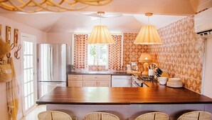 Una cocina con una isla central, dos lámparas colgantes y un salpicadero decorado.