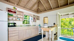 A kitchen with wooden cabinets, a refrigerator, a stove, and a window with a view of greenery. - Oceanfront Oasis: Contemporary Villa With Pool (North Palmetto Point)