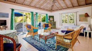 A spacious room with a high ceiling, wicker furniture, a glass coffee table, and large windows with curtains. - Oceanfront Oasis: Contemporary Villa With Pool (North Palmetto Point)