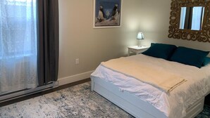 Un dormitorio con una cama, una mesita de noche, una lámpara, un espejo y un cuadro en la pared.