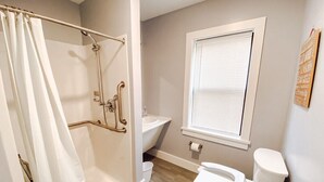 Baño con ducha, inodoro, lavamanos y ventana.