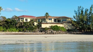 A beachfront property with two houses, a sandy beach, and dense vegetation. - Banks Road Bliss: Luxury Estate With Pool (South Palmetto Point)