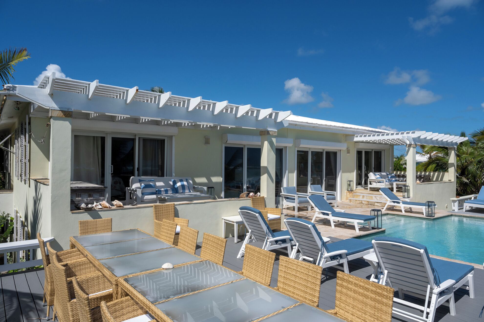 Area piscina con lettini, un tavolo da pranzo e una veranda coperta.