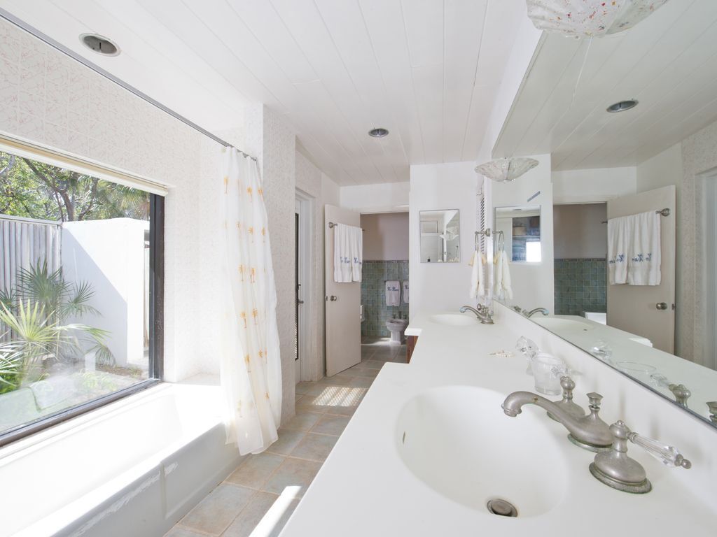 A modern bathroom with a large sink, a mirror, and a shower area.