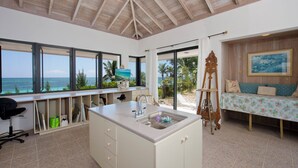 A kitchen with a large island, a dining area with a view of the ocean, and a wooden ceiling. - Tropical Hideaway: Charming Cottage Near Pink Sands Beach (Rock Sound)
