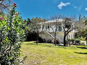Un edificio con una scala che conduce a un balcone, circondato da vegetazione e cielo sereno.