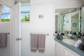 Un bagno con pareti rivestite di piastrelle bianche, un grande specchio e due asciugamani appesi a portasci.