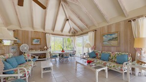 Una habitación amplia con techo alto, vigas de madera, zona de comedor y un conjunto de sofás.