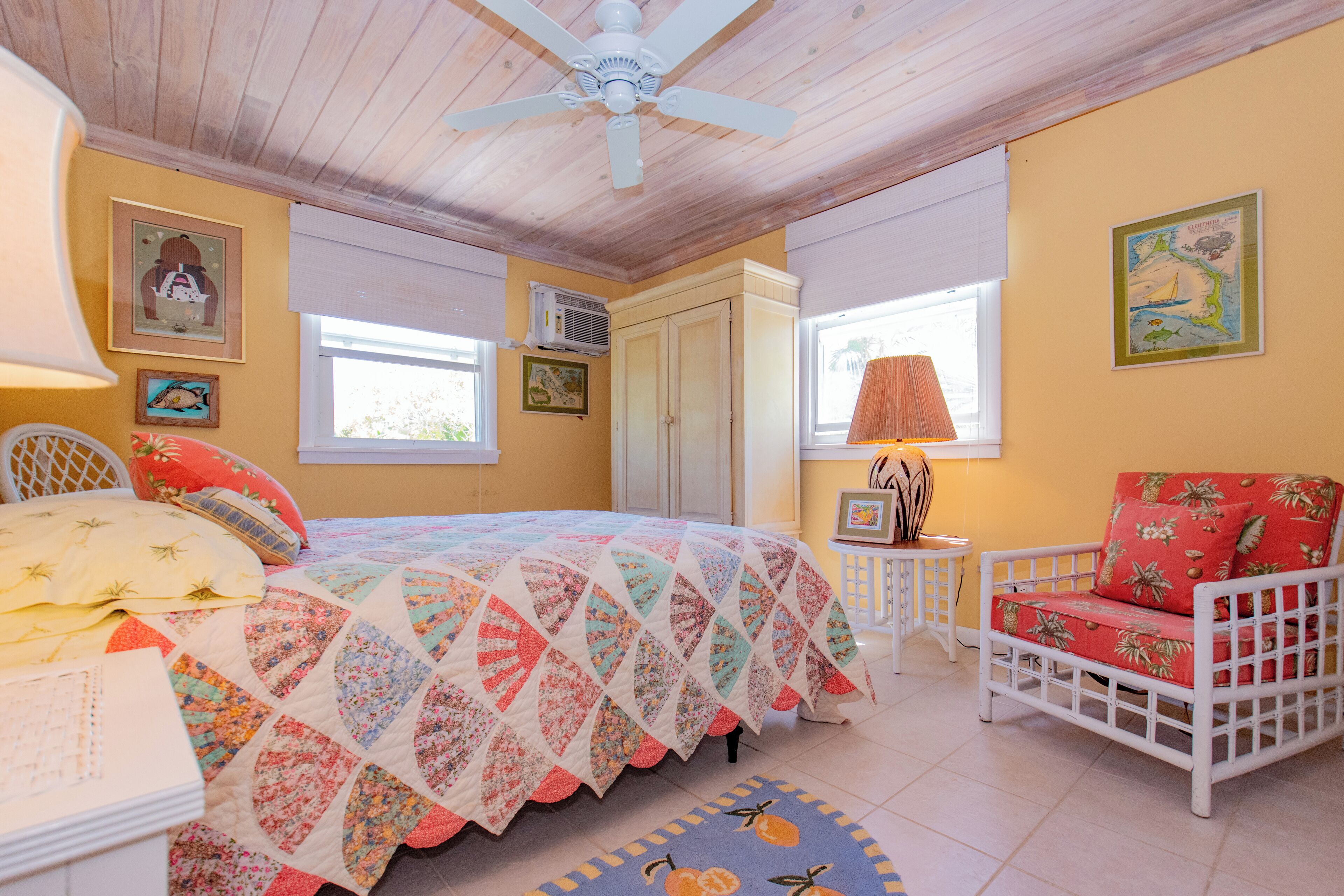 Une chambre à coucher avec un lit, une chaise, un ventilateur de plafond et une fenêtre.