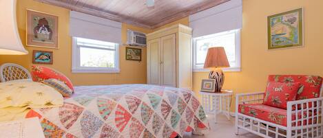 Une chambre à coucher avec un lit, une chaise, un ventilateur de plafond et une fenêtre.