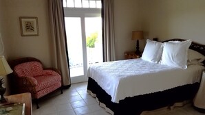 Une chambre d’hôtel avec un lit, une chaise, une lampe et une fenêtre avec des rideaux.