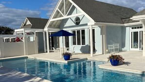Une piscine avec une maison blanche en arrière-plan.