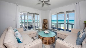 A spacious balcony with a view of the ocean, furnished with two sofas and a round wooden coffee table. - Secluded Luxury: New Beachfront Home With Pool (Gregory Town)