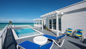 A pool area with a view of the ocean, deck chairs, and a pergola. - Secluded Luxury: New Beachfront Home With Pool (Gregory Town)