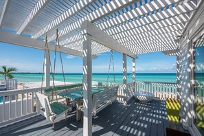 A covered outdoor area with a pool, seating, and a view of the ocean. - Secluded Luxury: New Beachfront Home With Pool (Gregory Town)