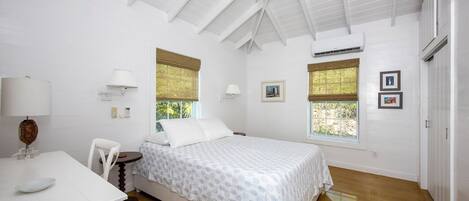 Un dormitorio con cama, escritorio, silla y ventana con persianas.