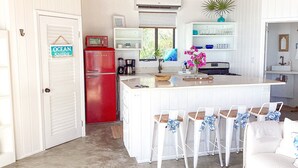 A compact kitchen with a red refrigerator, white cabinetry, and a central island with bar stools.