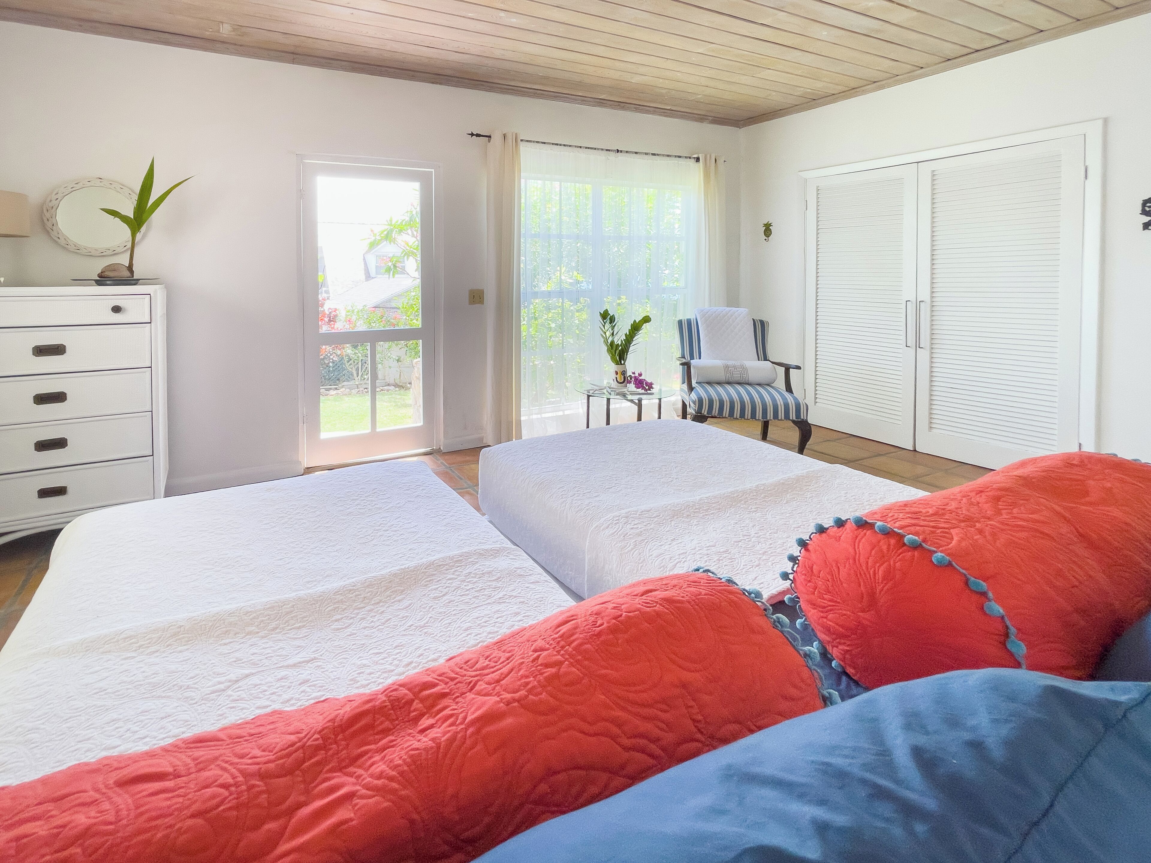 Une chambre avec deux lits, une commode, une chaise et une armoire.