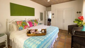Un dormitorio con cama, una bandeja de mimbre con juego de té, una silla y una puerta.