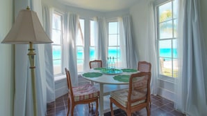 A dining area with a round table, chairs, and a lamp. - Captain'S Quarters: Restored Waterfront Home With Sunset Views (Governor's Harbour)