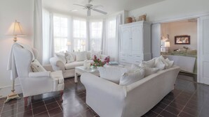 A spacious living room with a white sofa, a coffee table, and a ceiling fan. - Captain'S Quarters: Restored Waterfront Home With Sunset Views (Governor's Harbour)