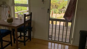 A room with a wooden table and chairs, a window with a view of the sea, and a door with a view of the garden. - Historic Hideaway: Restored Waterfront Estate (Governor's Harbour)