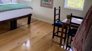 A room with a bed, a table with chairs, a window with curtains, and an air conditioning unit. - Historic Hideaway: Restored Waterfront Estate (Governor's Harbour)
