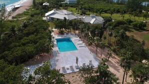 An aerial view of a resort with a swimming pool, lounge chairs, and a beach. - Windermere Paradise: Luxurious Estate With Amenities (Governor's Harbour)