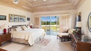 A bedroom with a large bed, a wooden ceiling, a balcony with a view, and a painting on the wall. - Windermere Paradise: Luxurious Estate With Amenities (Governor's Harbour)