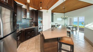 A modern kitchen with dark cabinetry, stainless steel appliances, and a large island. - Contemporary Comfort: Stunning Villa With Pool & Restaurant (Governor's Harbour)