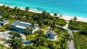 A coastal property with multiple buildings, a beach, and palm trees. - Pink Sand Paradise: Luxury Home With Heated Pool (North Palmetto Point)